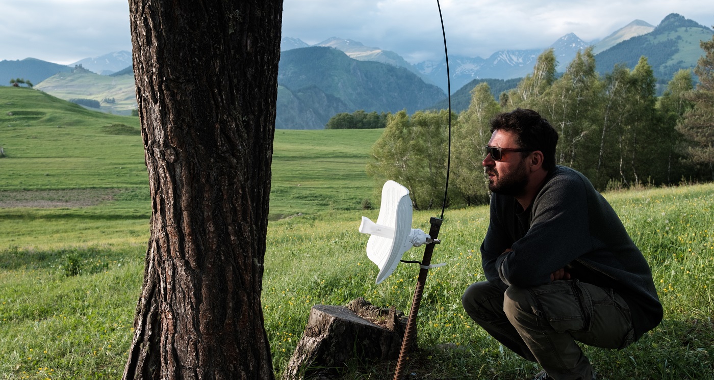 a man in a field checking if antenna is aligned