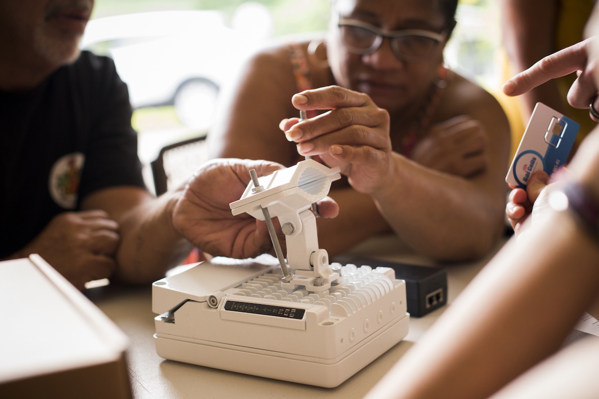 A diverse group of people focuses on a small electronic device
