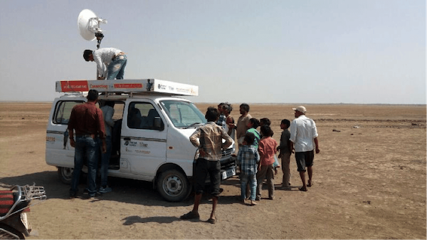 Gente reunida alrededor de un vehículo con antena