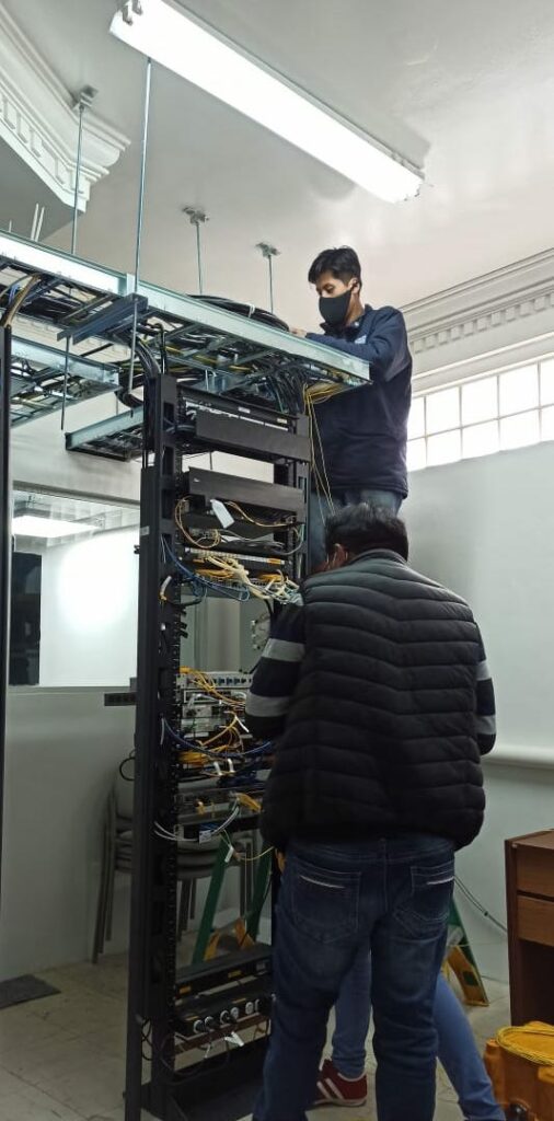 Two men installing cables in a room