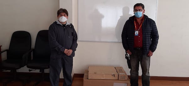 Two men wearing face masks standing between carton packages