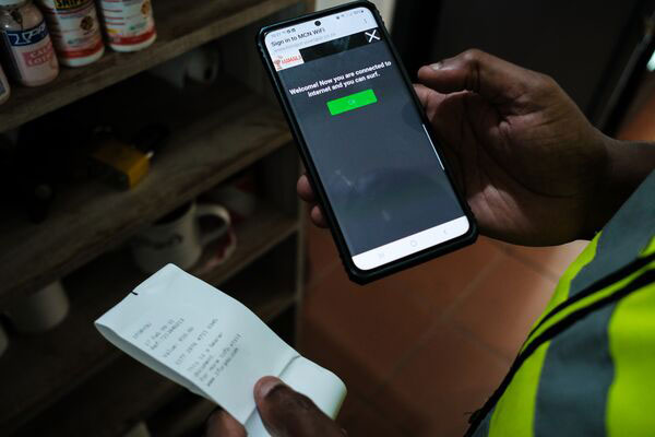 Un hombre con un teléfono en una mano y un papel en la otra mano