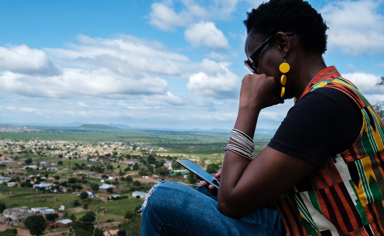 a woman looking at the phone sitting at the top of the hill