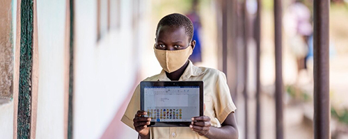 Child wearing mask and holding a tablet