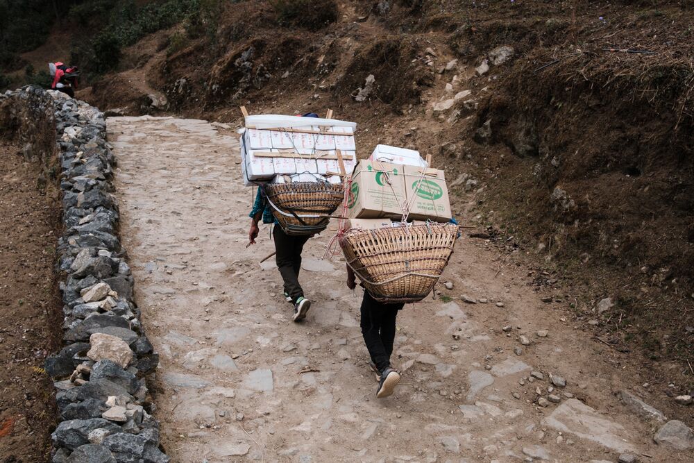 Porteadores cargando cestas y cajas a la espalda
