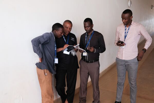 Four men standing next to the wall and looking at the notebooks