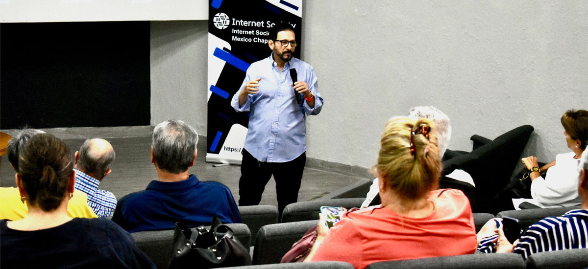 A man stands and speaks to seated people