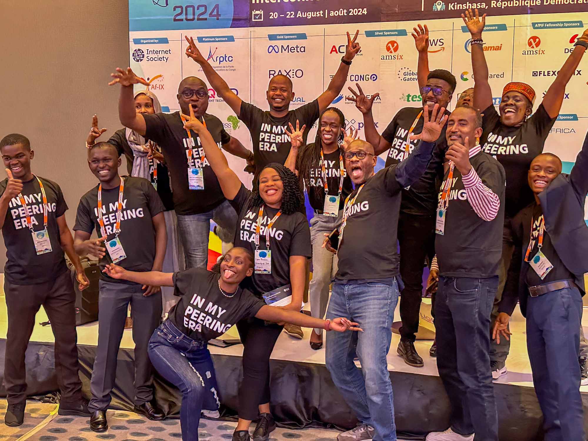 A group of people wearing black shirts pose excitedly for a photo