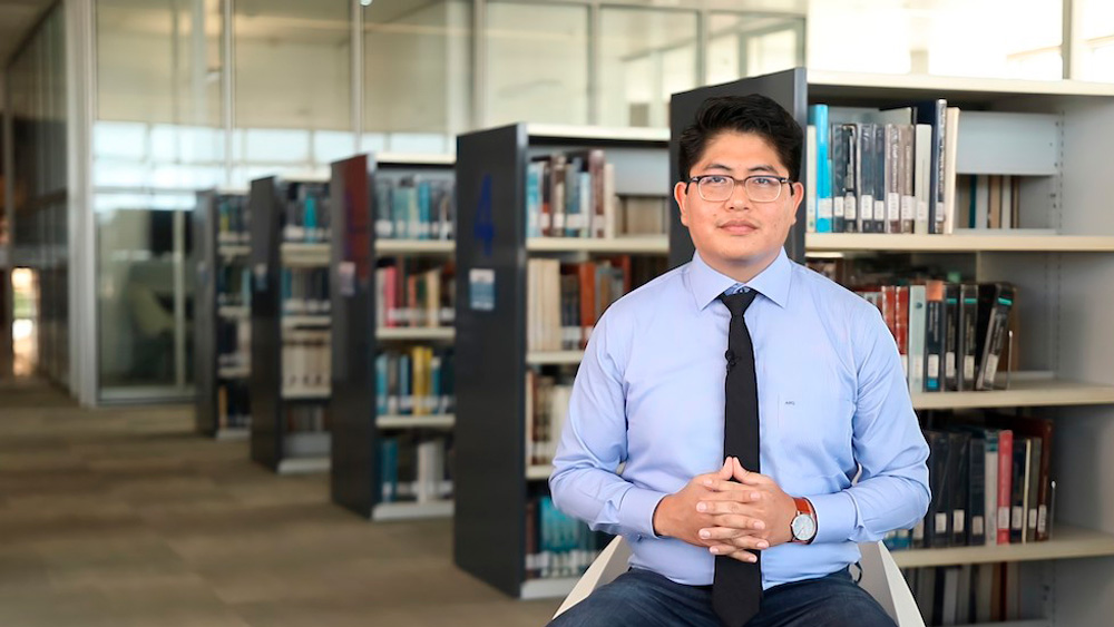 Alan Ramírez sits in a library.