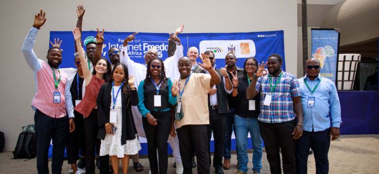 a group of people stand together, smile, and raise their arms