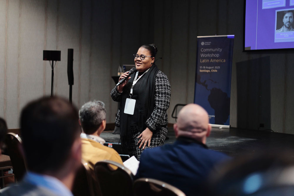 Whitney Kimberly Douglas-de Rijp stands and speaks into a microphone