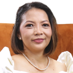 A woman in a white dress sits gracefully on an orange couch