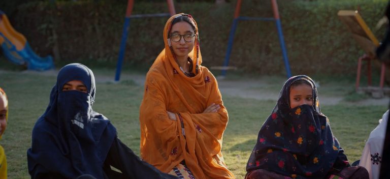 Three women sit on the grass outside