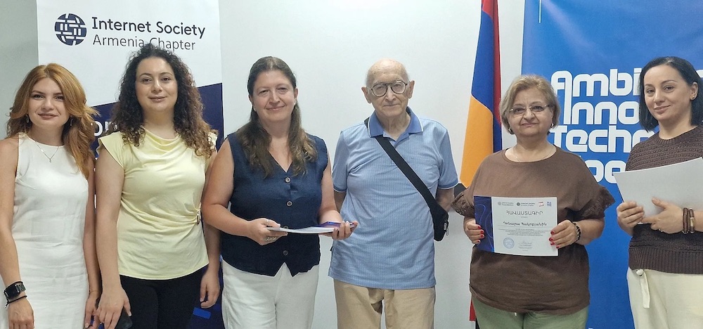 Six people stand together in front of an Internet Society Armenia Chapter sign